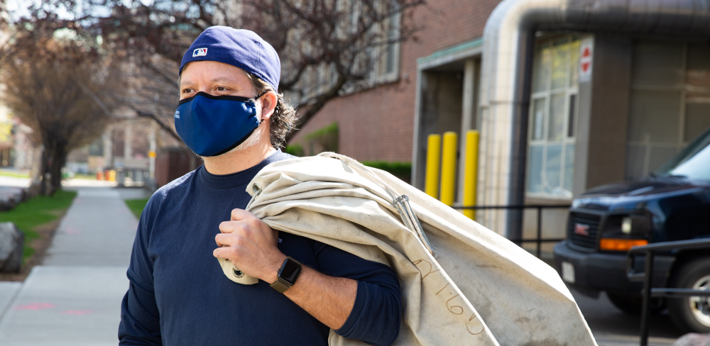 A mail person carries a mail bag on campus.